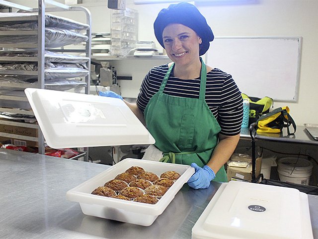 Andrea Macgee with a plastic container of her muffins in the kitchen at FEED Kitchens.