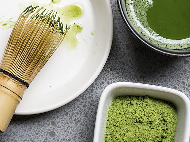 Powdered green matcha tea with a bamboo whisk and made tea.