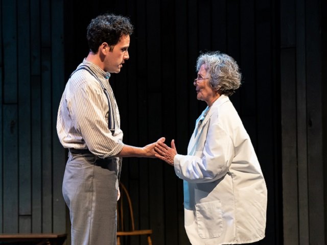 A young man and an older woman face each other on stage.